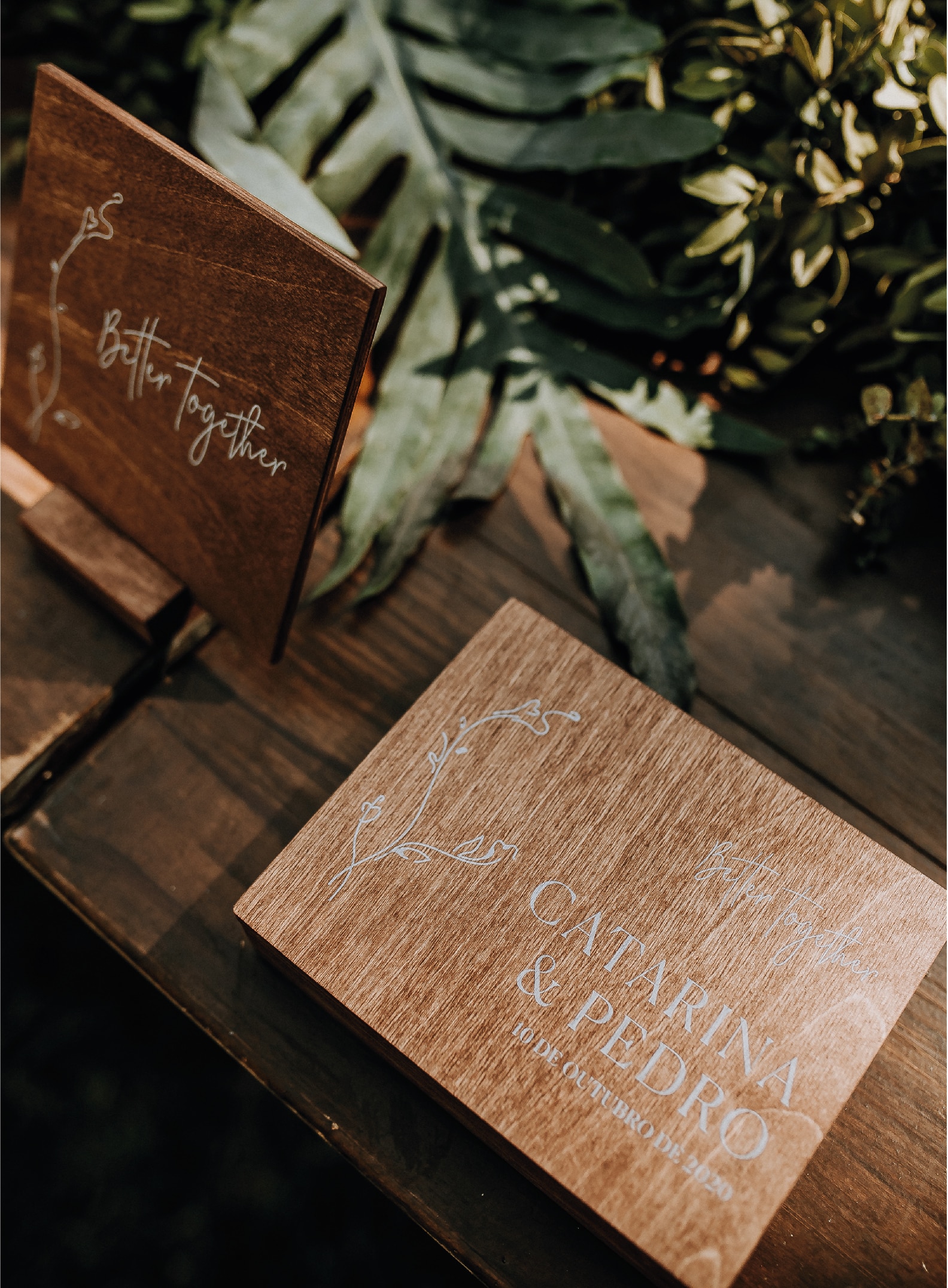 Caixa das alianças da atriz Catarina Gouveia do estilo floral feita de madeira com tipografia branca numa mesa de madeira