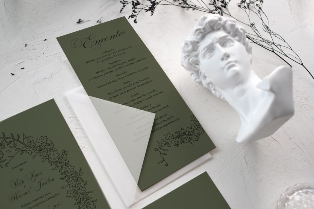Ementa de casamento verde de estilo geometrico com desenhos florais e um envelope branco transparente
