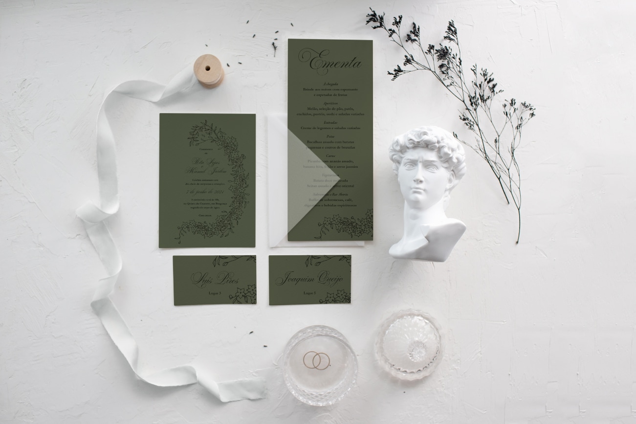 Estacionário de casamento com suportes verdes de estilo florar e caligrafia preta com um envelope branco transparente