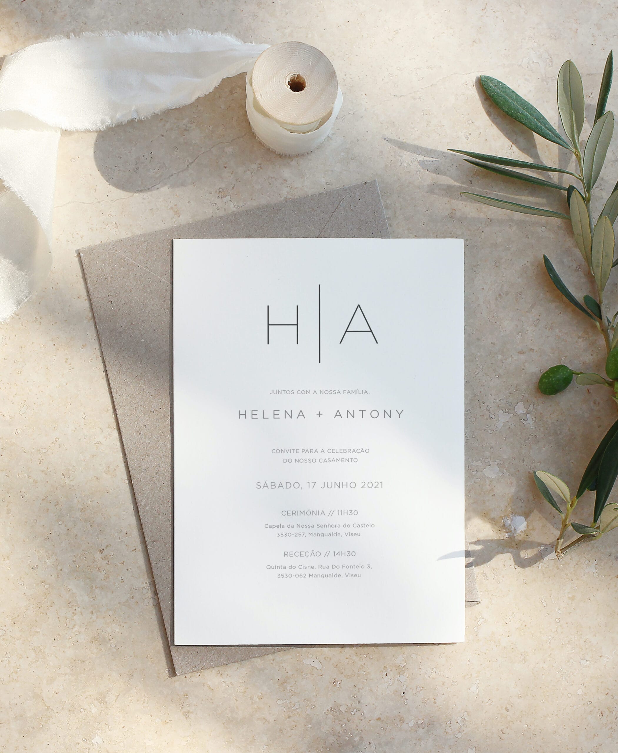 Convite de casamento de estilo tipográfico branco com um envelope castanho com uma fita de linho e folhas de oliveira