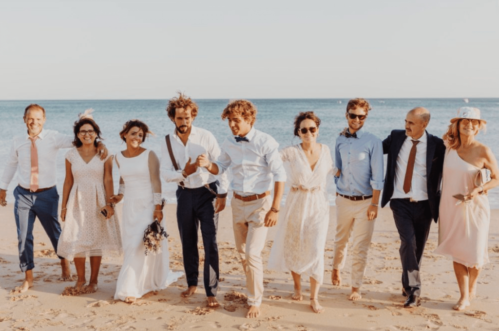 fotografia de casamento com os noivos e a familia na areia com vista para o mar
