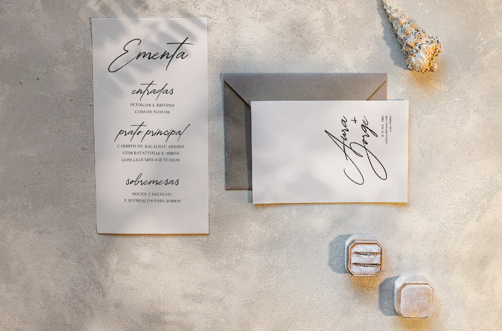 Convite de casamento de estilo tipográfico com envelope cinzento e búzios do mar e caixa de alianças