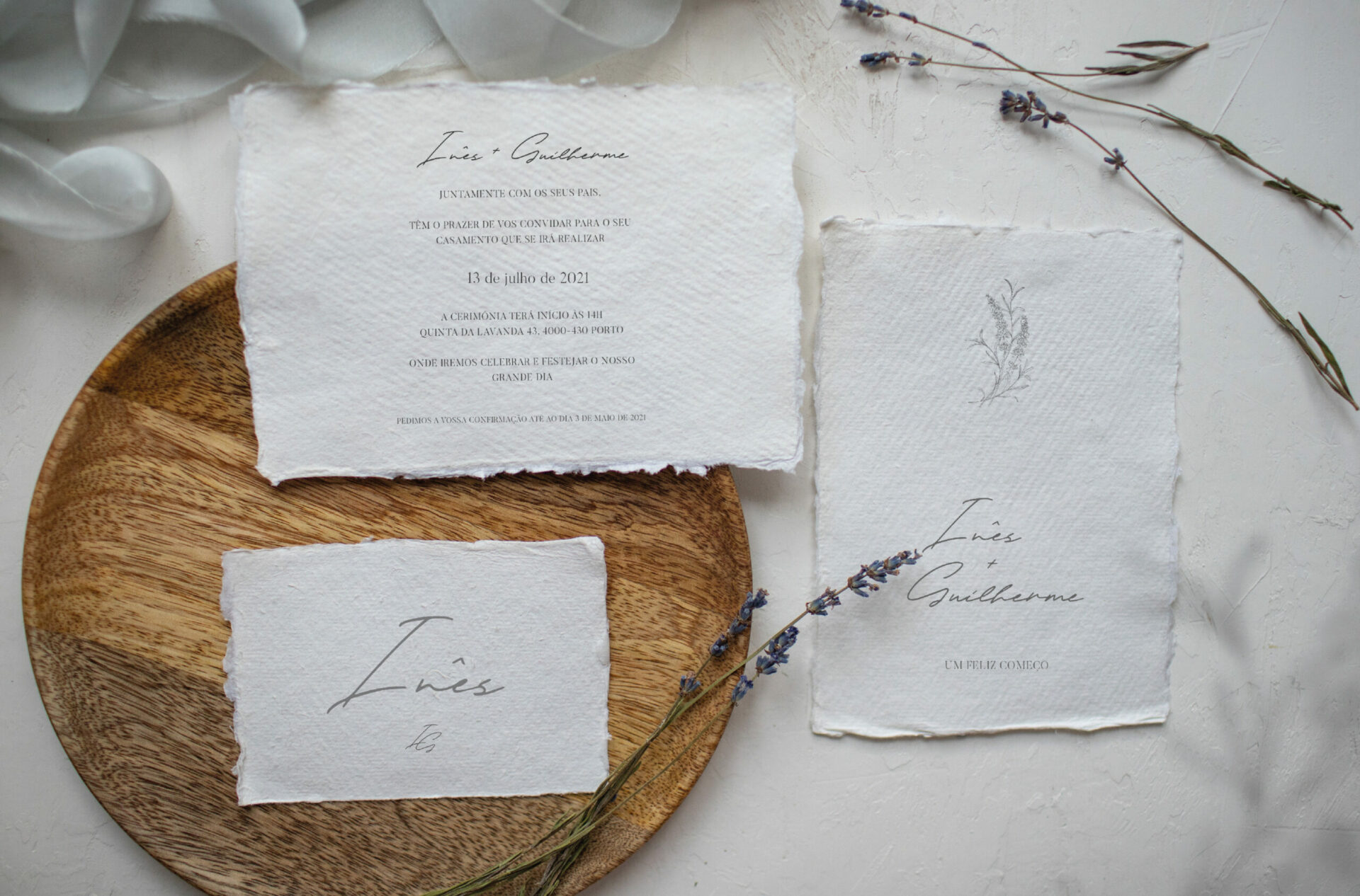 Convite de Casamento branco de estilo tipografico com acabamento rasgado com flores de lavanda e uma base de madeira castanha