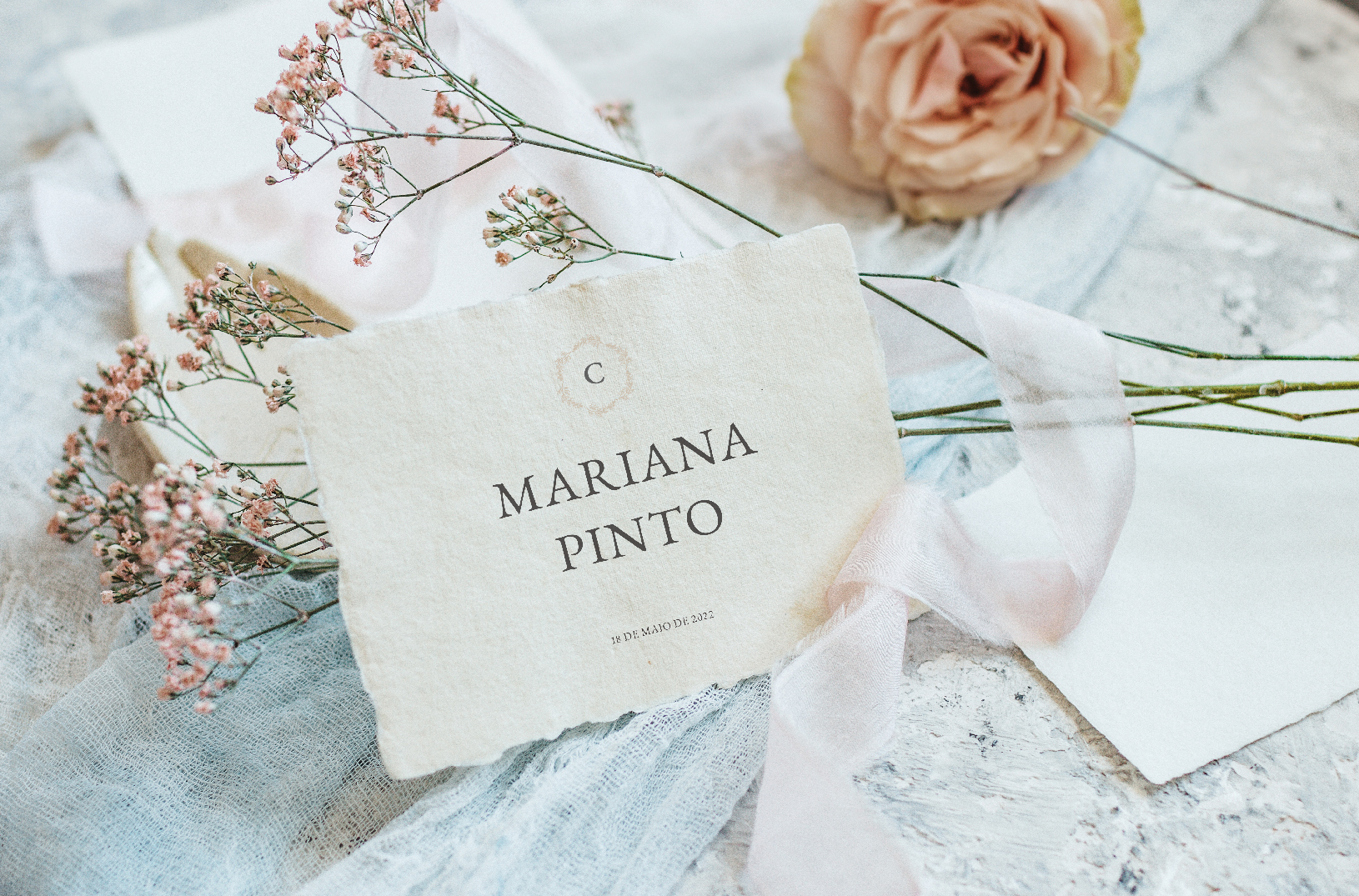 Convite de casamento branco de estilo tipográfico com acabamento rasgado, com fitas rosa e azul e flores rosa