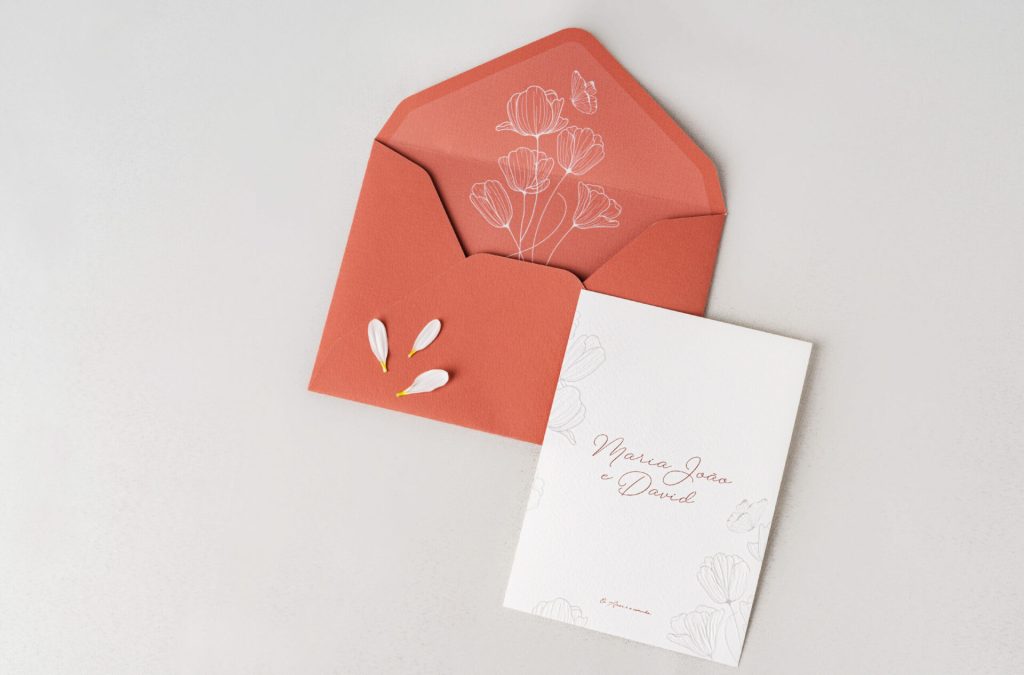 Convite de casamento branco de estilo floral com um envelope de cor salmão com uma barra de lacres branca