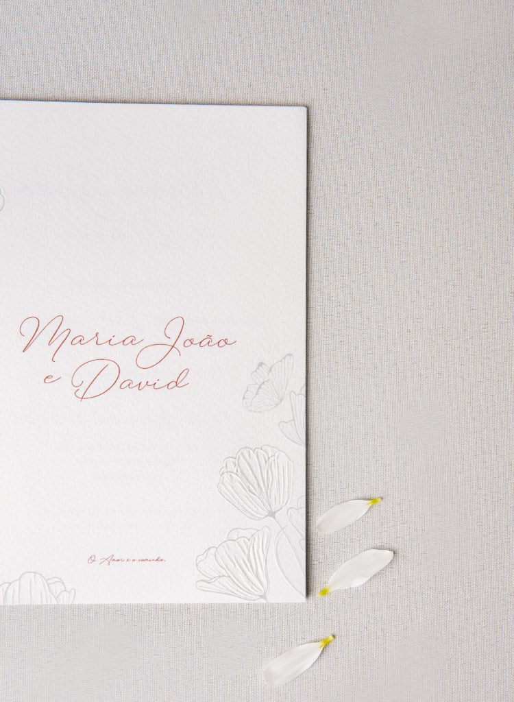 Convite de casamento branco de estilo floral com petelas brancas.